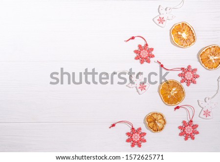 Christmas wooden toys in the form of a white angel, a red snowflake, dried orange slices for decoration with a place for copy space with a flat lay on a white background. View from above