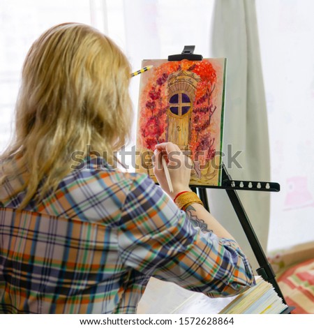 female artist illustrator creates a image on an easel (the inscription in the picture in French is “bougainvilleas”)
