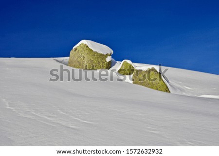 Snowy mountains winter landscape on bright clear blue sky background. Sunny snowy day in the mountains. Snow covered white mountain peaks. Snowy mountain ranges. White snowcapped mountains in Siberia.