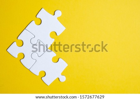 Three pieces of a puzzle united among themselves on a yellow background. Teamwork concept. Close up. Royalty-Free Stock Photo #1572677629