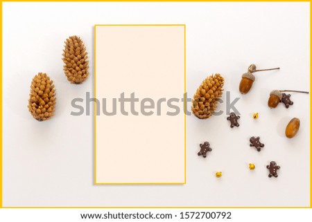 Warm Christmas background with pines, acorns and gingerbread men cookies with rectangular frame in gradient white background with copy space 
