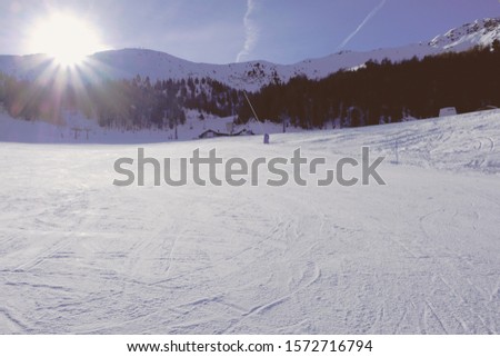 Winter landscape with mountain slopes covered with snow in a beautiful sunny day. Wide empty ski-track at Pila ski resort in the Italian Alps. Winter holidays destination.