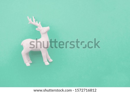 White deer on pastel mint background, top view, flat lay style. Space for text. Christmas or New year celebration concept.
