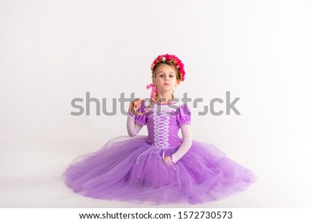 Little blonde girl wearing purple fairy princess dress on white background. Kids costume for new year party.