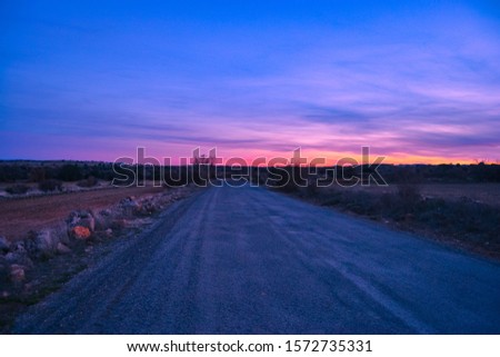 RED SUNSET LANDSCAPE ON A COUNTRYSIDE ROAD violet red colors	