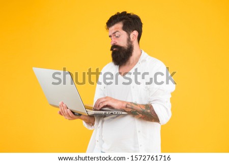 concentrated hipster use notebook. Bearded man laptop yellow wall. shopping online. Successful developer. education in digital world. Programming brutal man surfing internet. concentrated on work.