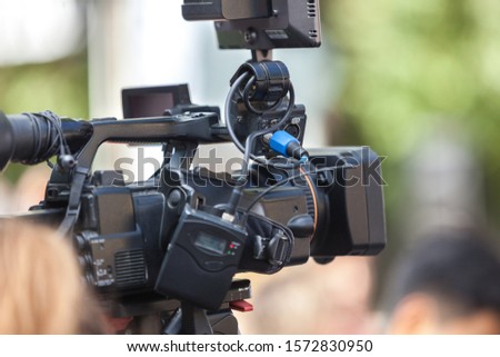 Man journalist with a modern large black video camera on bokeh background