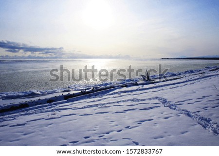 Lake Baikal. Siberia. A winter sun hanging low over the horizon is reflected on the surface of the Lake Baikal. The snow on the shore shines white.