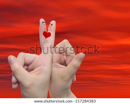 Concept or conceptual human or female hands with two fingers painted with a red heart over a sunset sky background for valentine, romantic, love, couple, young, family or wedding