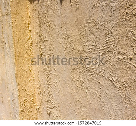 Rough texture of a large light tan colored weathered painted concrete  wall may be ideal for a grungy textured background.