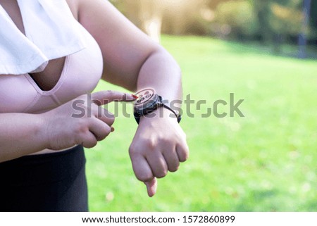 Asian overweight  sports runner in sports suit monitors her heart rate after running in city park, picture shows the heart rate graphic from the monitor, Concept of good health, close up