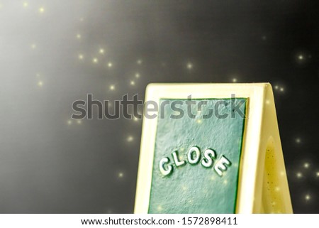 Close up of a green ,yellow with white "CLOSE" chalkboard sign leaning against sparkle ,bright with black background.