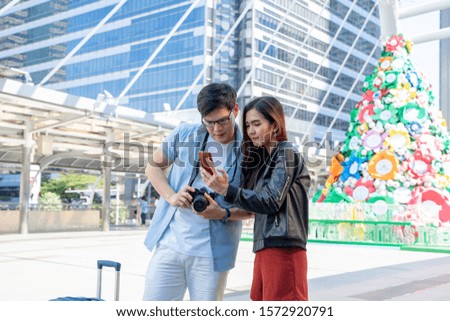 Couple of tourists consulting a city guide and use smartphone gps searching for directions searching locations.