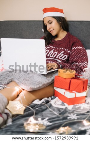 Woman laying in bed with laptop and presents