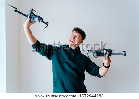 Guy holds two quadrocopters against a wall