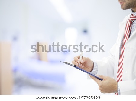 Male doctor filling out medical document. 