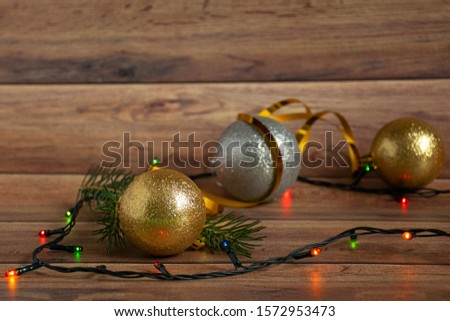 Gold and silver Christmas balls and multi-colored garland on a wooden Christmas background. Copyspace.
