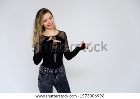 Concept of a woman talking to the camera. A photo of a pretty smiling girl with long beautiful curly hair in a black T-shirt on a white background is standing right in front of the camera.