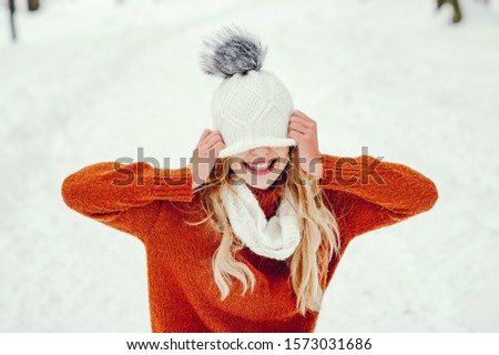 Cute girl have fun in a park. Woman in a knited sweater.