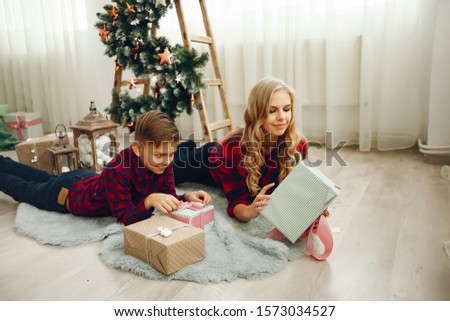 Beautiful mother in a red shirt. Family sitting near christmas gifts. Little girl and boy near christmas tree