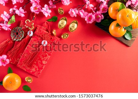 Chinese new year festival decorations pow or red packet, orange and gold ingots or golden lump on a red background. Chinese characters FU in the article refer to fortune good luck, wealth, money flow.