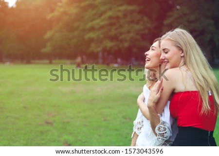 Beautiful woman with friend playing or relaxing in a park in vacation day, portrait of caucasian girl or traveler hug together and posing