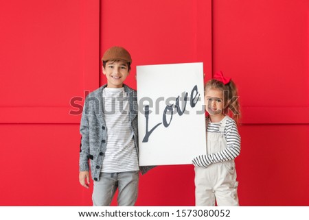 Cute little children holding picture with word LOVE on color background. Valentines Day celebration