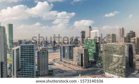 Dubai's business bay towers at morning aerial timelapse. Rooftop view of some skyscrapers and new towers under construction. Clouds on a blue sky and traffic on roads