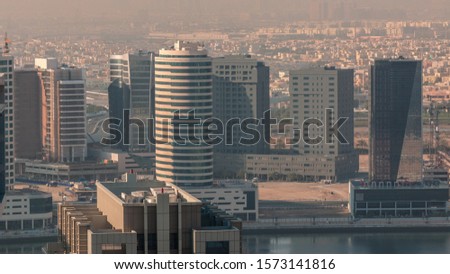 Dubai's business bay towers at morning aerial timelapse. Rooftop view of some skyscrapers and new towers under construction. Hazy weather with shadows mooving fast