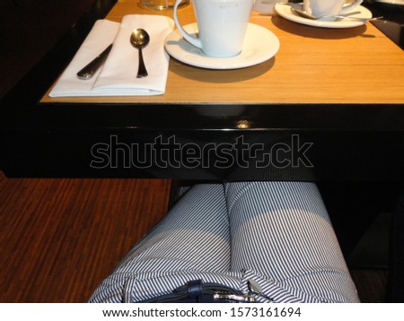 part of the legs and a Cup of coffee on the table
