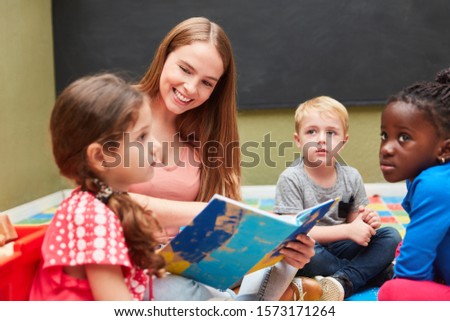 Teacher and children group reading from a children's book in kindergarten