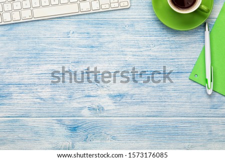 Background with computer keyboard,  coffee cup and utensils arranged on blue wooden desktop. Large copy space.