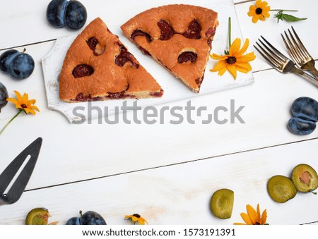  slices of biscuit plum cake on a white wooden board and fresh fruits, top view