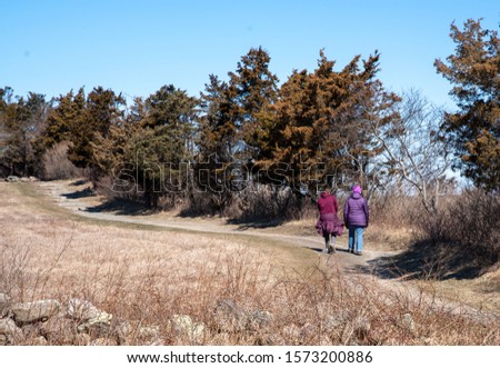 Mother and daughter walking on a path in an open marsh on an early spring day with room for copy
