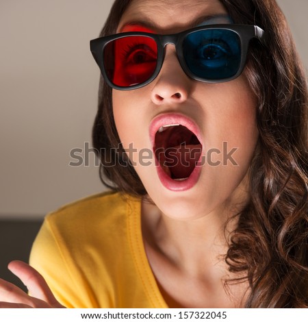 Expressive young woman watching 3d film in stereo glasses