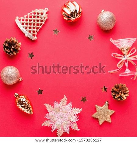 Christmas baubles, golden and pink decorations round frame, confetti on red background with copy space. Christmas card with ornaments, top view