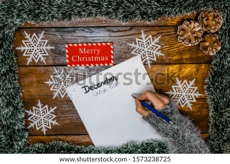 Hand writing on paper Wish list for December. Christmas decorations on wooden board. Christmas concept.