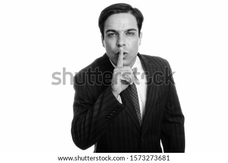 Studio shot of young Persian businessman with finger on lips isolated against white background