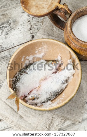 Two roaches fish in ceramic bowl with salt., near the old cutlery. From the series "Still Life with fresh fish"