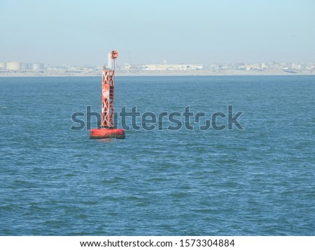 Seascape of buoy sways and floating in the sea  as safety warning and navigation marker at harbor or port on a sunny day. mew perched on buoy