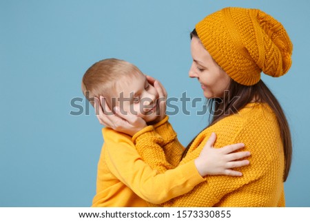 Woman in yellow clothes have fun posing with cute child baby boy 4-5 years old. Mommy little kid son isolated on blue background studio portrait. Mother's Day love family parenthood childhood concept