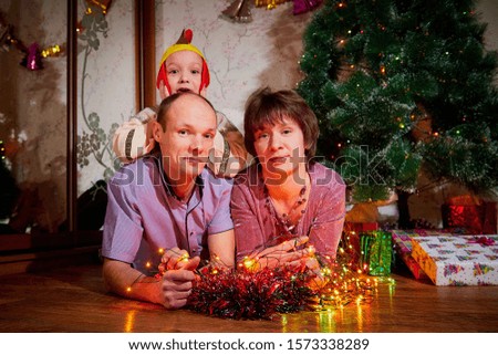 Family consisgitng mother, father and son in carnival costumes at Christmas or new year near the Christmas tree in the room. Mom, dad and boy indoor indoor posing together