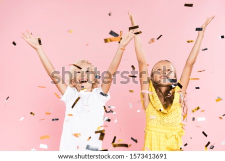 smiling kids with outstretched hands near falling confetti on pink background 