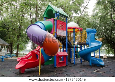 Colorful children playground activities in public park surrounded by green trees. Modern playground for childhood concept.