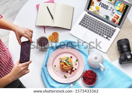 Food blogger taking photo of her breakfast at table, top view
