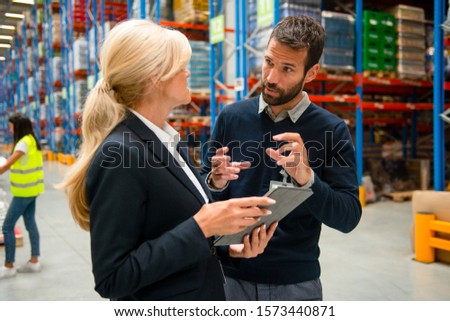 Supervisor taking inventory check with warehouse manager
