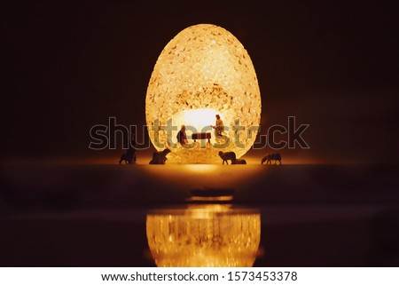 Miniature people child Jesus Christ in the manger with Mary and Joseph in egg sparkle light.Christmas concept.