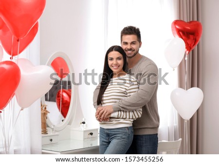 Lovely young couple in room decorated with heart shaped balloons. Valentine's day celebration