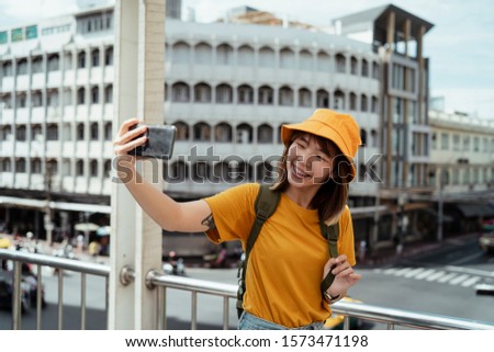 Backpacker girl take a selfie on a skywalk on the junction with her smiling face.