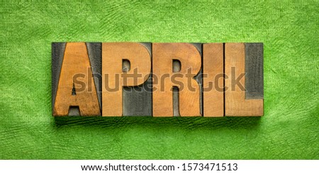 April month banner - word in vintage letterpress wood type against green handmade textured paper - calendar concept